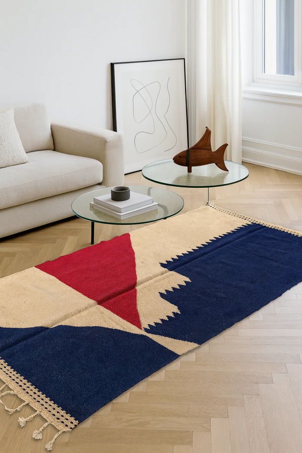 Zanafi flatweave rug in deep plum and ivory, featuring stepped triangle motifs, styled in a bright living room with neutral seating.