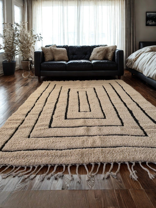 Beige area rug with black patterns on a wooden floor in a living room setting.