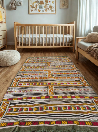 Nursery room with wooden crib, patterned rug, and wooden floor.