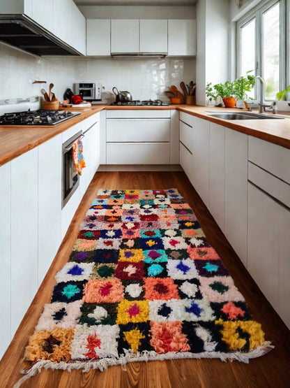 Colorful kitchen rug on a wooden floor with white cabinets and appliances.