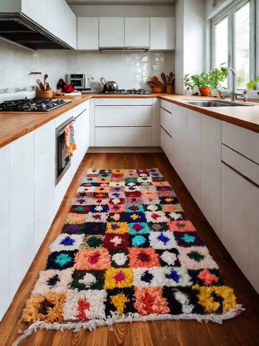 Colorful kitchen rug on a wooden floor with white cabinets and appliances.
