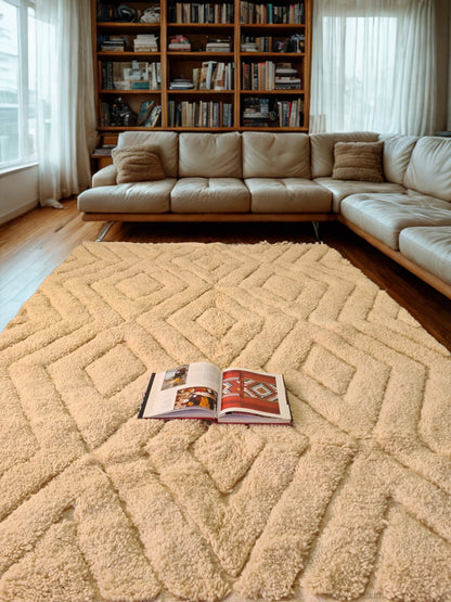 Beige sectional sofa in a living room with a patterned rug and an open book.