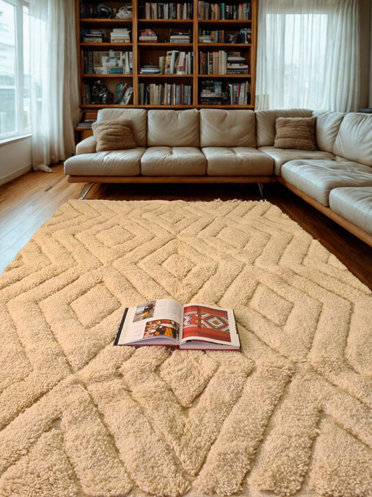 Beige sectional sofa in a living room with a patterned rug and an open book.