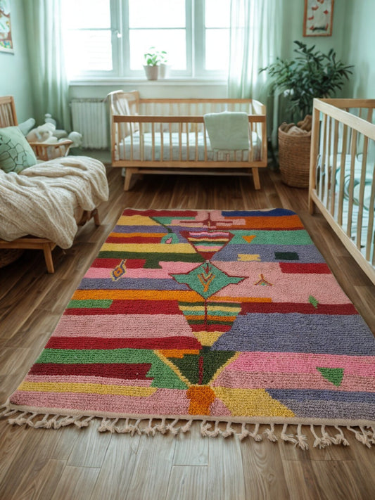 Colorful geometric-patterned rug in a nursery with wooden cribs and decor.