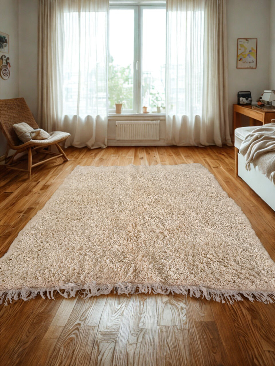 Beige shaggy rug on a wooden floor with a chair and window in the background