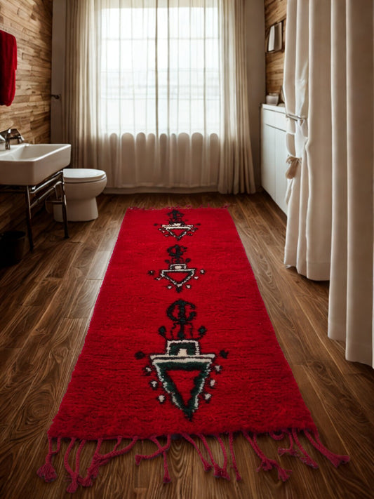 Red patterned rug on a wooden floor in a bathroom with white curtains and fixtures.