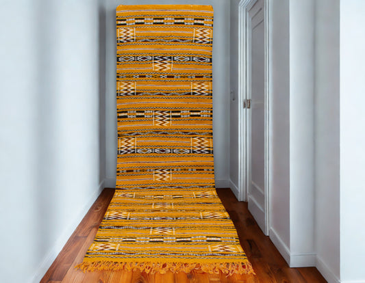 Yellow patterned rug on a wooden floor in a room with white walls.