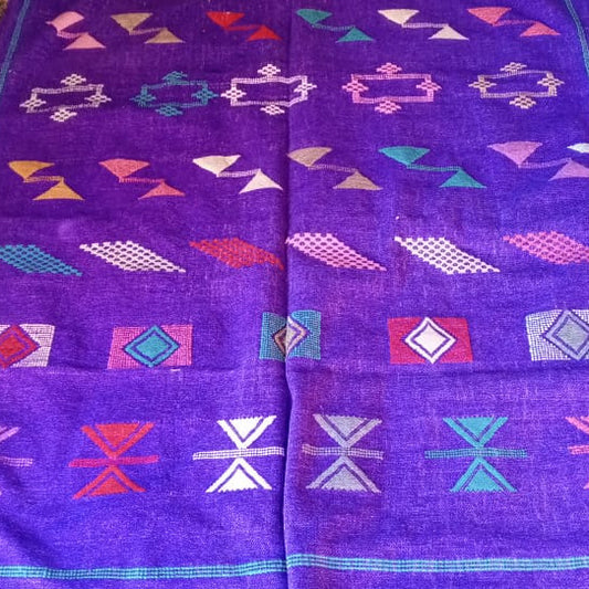 A purple Moroccan-style woven rug laid flat on a tiled floor, featuring colorful geometric patterns and borders.