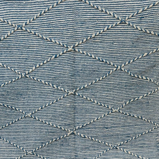 A blue and white woven Moroccan-style rug with a diamond pattern, draped over a white support in what appears to be a store or home interior.