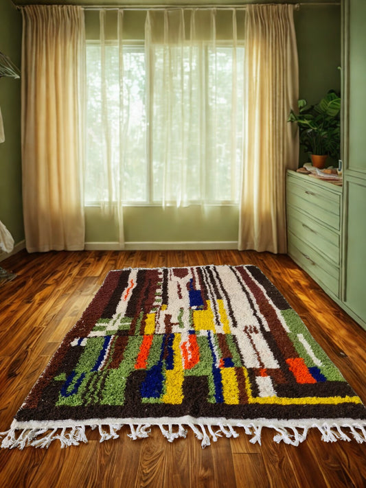 Colorful geometric-patterned rug on a wooden floor with sheer curtains in the background.