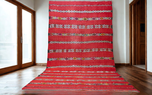 Red patterned rug on a wooden floor with large windows in the background