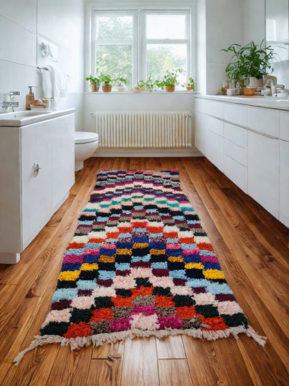 Colorful patterned rug on a wooden floor in a bathroom with white cabinets and plants.