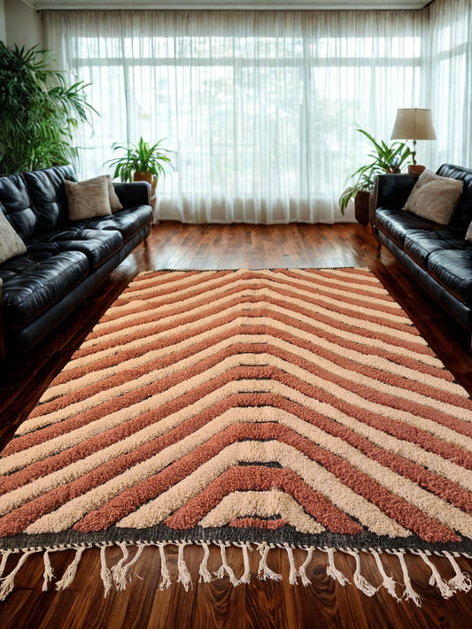 Living room with a chevron patterned rug, black leather couches, and plants.