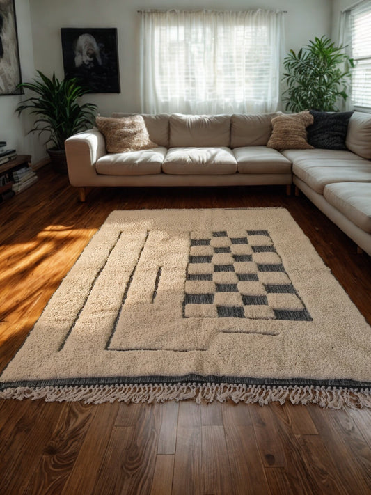Beige sectional sofa with a checkered rug in a living room setting.